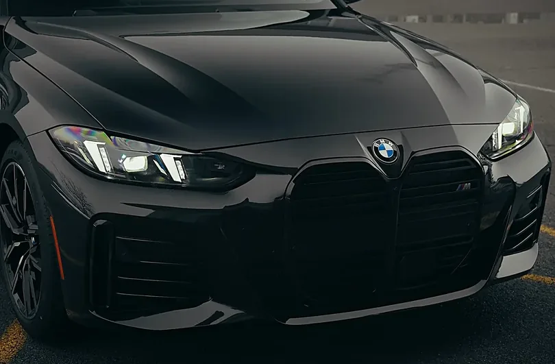 The front end of a black car after a premium detail, paint reflecting cleanly